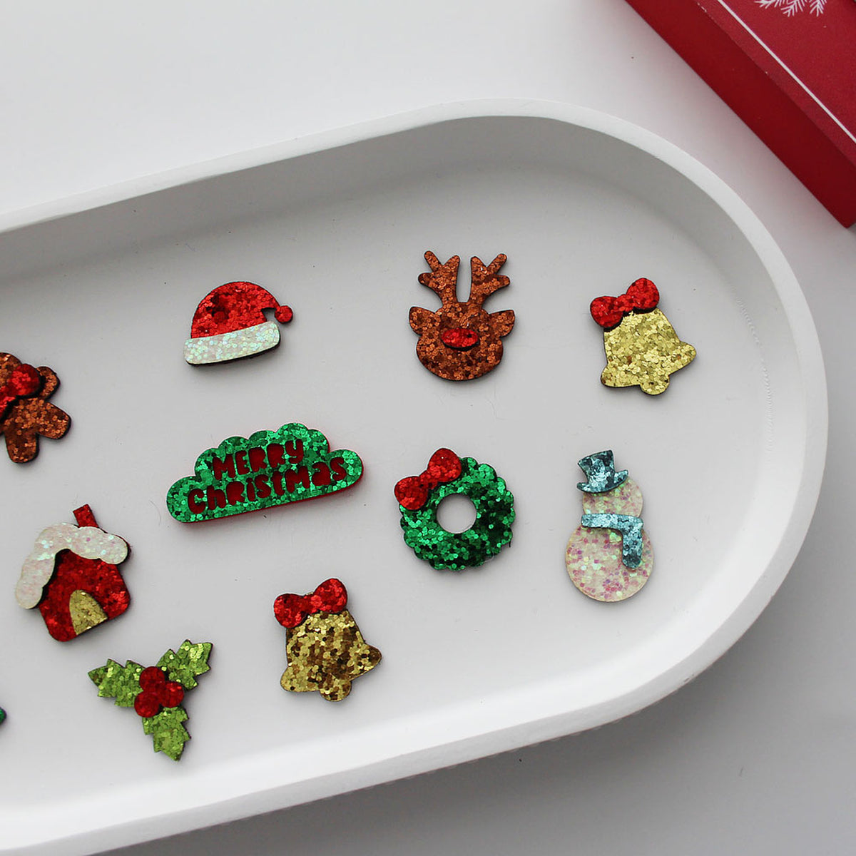 Christmas glitter applique shapes on white tray, Santa hat reindeer wreath bells and snowman