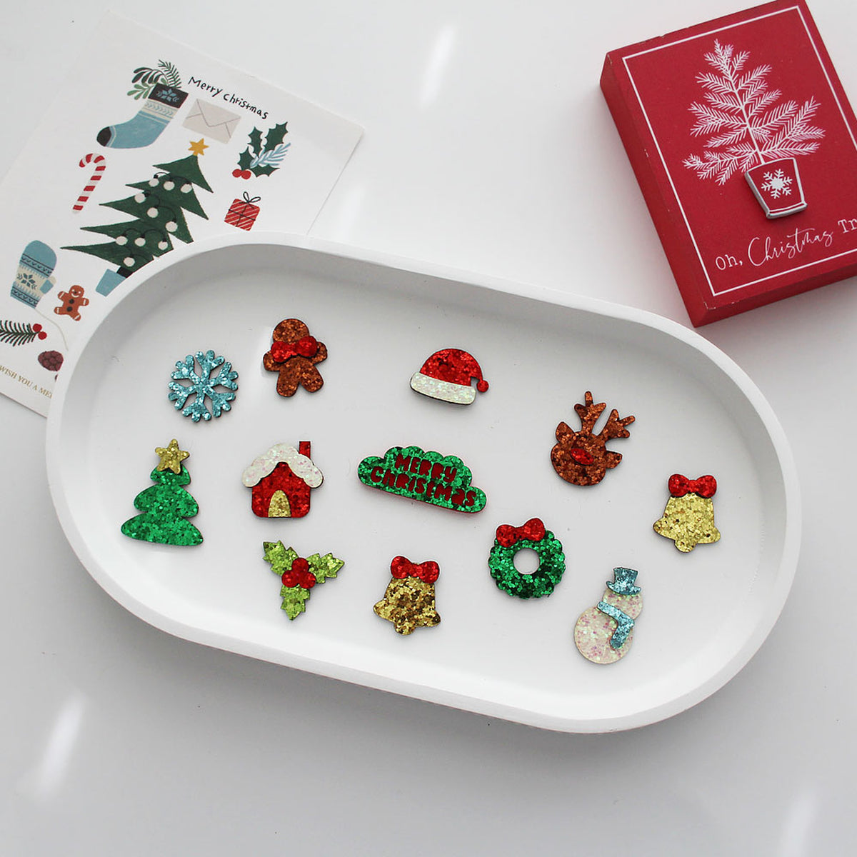 Christmas glitter embellishments on white tray with gift box